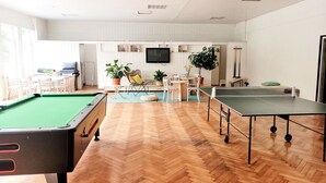 A spacious indoor recreational area with a pool table, ping pong tables, and a billiards table.