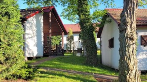A rustic building with a red roof, surrounded by lush greenery and a clear sky. - Beach Club-Häuser direkt am Strand by Interhome (Dziwnówek)