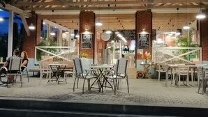 An outdoor cafe with tables and chairs, a wooden ceiling, and hanging lights. - Beach Club-Häuser direkt am Strand by Interhome (Dziwnówek)