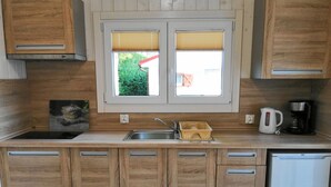 Cucina con mobili in legno, un lavello a due vasche, una macchina da caffè e un frigorifero.