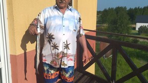 A man standing on a wooden deck holding two fish, with a dog nearby. - Ferienanlage Belona/A1 by Interhome (Niechorze)