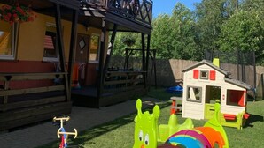A wooden house with a balcony, a playhouse, and a green toy vehicle on the lawn. - Appartements mit einem Wohn-,Ess- und Schlafraum und kleinem Balkon für vier Pe by Interhome (Niechorze)