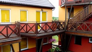 A building with a yellow facade, wooden balconies, and a red roof. - Appartements mit einem Wohn-,Ess- und Schlafraum und kleinem Balkon für vier Pe by Interhome (Niechorze)