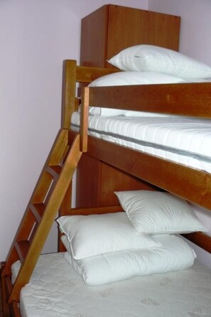 A bunk bed with a wooden ladder, white bedding, and a wooden wardrobe in the background. - Appartement mit einem Wohn-,Ess- und Schlafraum und kleiner Terrasse für vier P by Interhome (Niechorze)