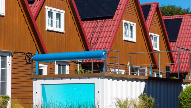 A row of wooden houses with red roofs and a blue awning over a garage. - "Kapitanski" mit Schwimmbad by Interhome (Rewal)