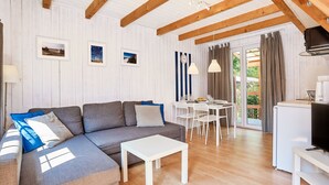 A modern living room with a grey sectional sofa, white coffee table, and a dining area with white chairs. - Bootshaus mit Schwimmbad by Interhome (Rewal)