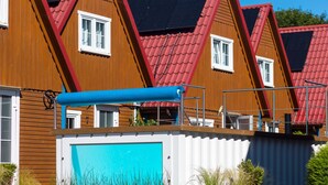 En rad med trähus med röda tak och ett blått markis över ett garage.