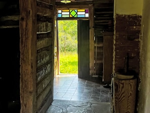 A hallway with a wooden door leading to a bright outdoor area.