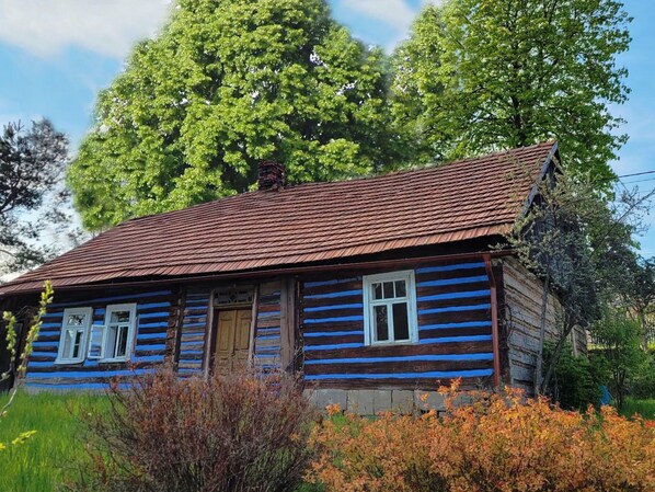 Una cabaña de madera tradicional con techo inclinado, revestimiento de madera y chimenea.
