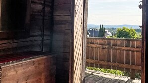 A wooden interior with a view of a fenced outdoor area and distant buildings.