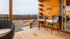 A wooden deck with wicker chairs and a view of a forested landscape. - Brand New Luxury 7 BR Cabin w Hot Tub, Game Room (McHenry)