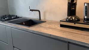 A modern kitchen with a large island, stainless steel appliances, and pendant lighting. - in Dirkshorn by Interhome (Dirkshorn)