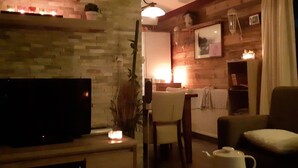 Un salón acogedor con chimenea, televisor y comedor con mesa y sillas.