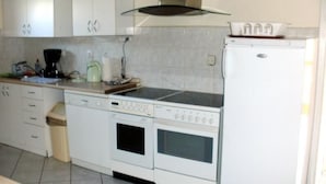 A kitchen with white cabinets, a stove, a sink, and a refrigerator. - Villa Regina by Interhome (Sebestenice)