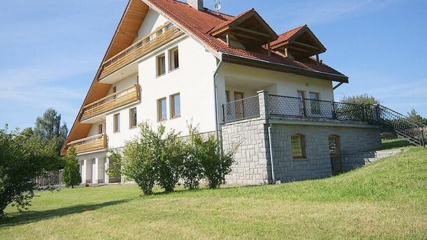 A two-story house with a sloped roof, a balcony on the upper floor, and a stone foundation. - Villa Regina by Interhome (Sebestenice)