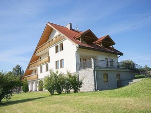 A two-story house with a sloped roof, a balcony on the upper floor, and a stone foundation. - Villa Regina by Interhome (Sebestenice)