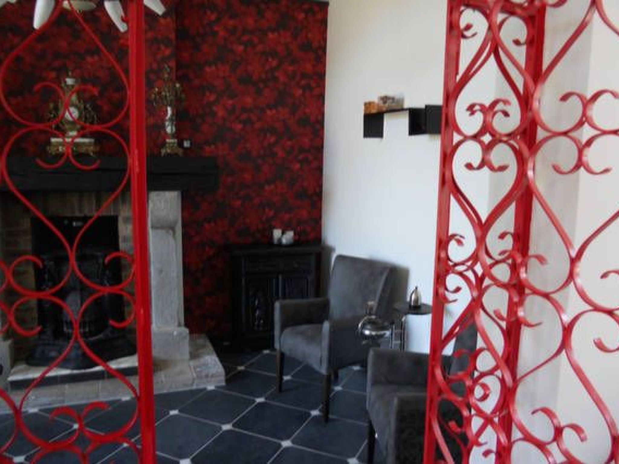A room with a fireplace, a red decorative partition, and a tiled floor.