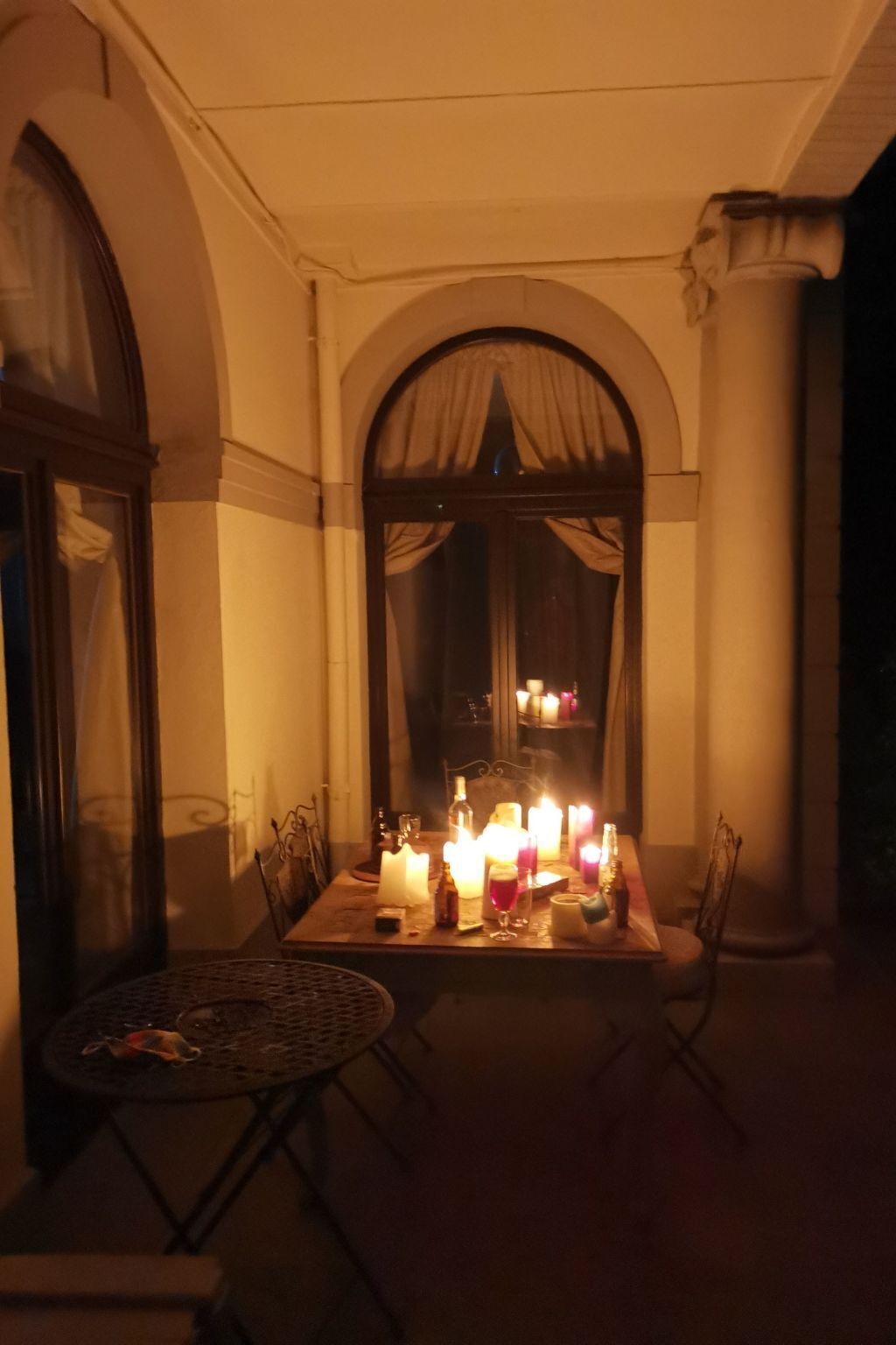 An intimate dining area with a table set for two, surrounded by chairs, and illuminated by candles.