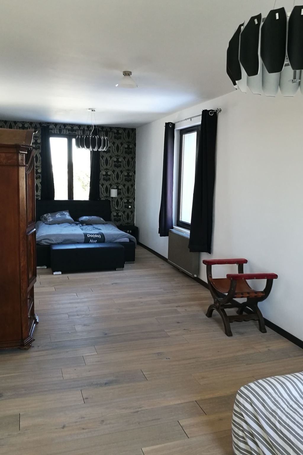 A room with a bed, a wooden dresser, a small table, and a window with curtains.