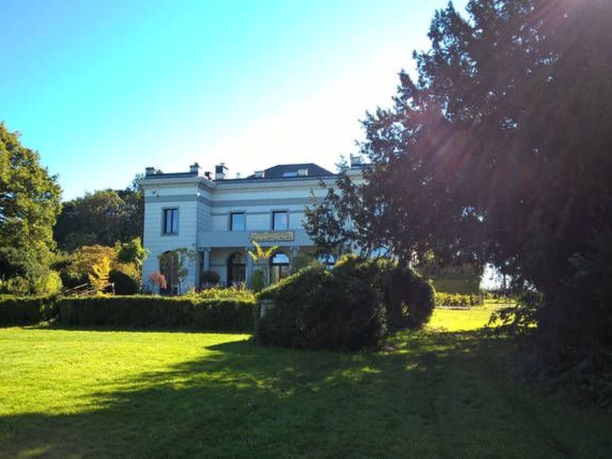 A large, two-story building with a symmetrical facade, a central entrance with a canopy, and a well-maintained lawn in the foreground.