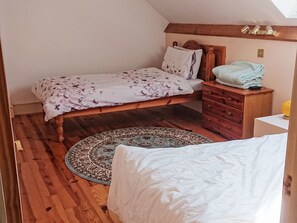 A bedroom with a bed, a wooden dresser, a nightstand, a patterned rug, and a window with a view. - Haus in Crickadarn mit Parkplatz und Bergblick by Interhome (Crickadarn)