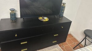 Een zwarte tv-kast met een flatscreen televisie, twee decoratieve vazen en een geruit dienblad.