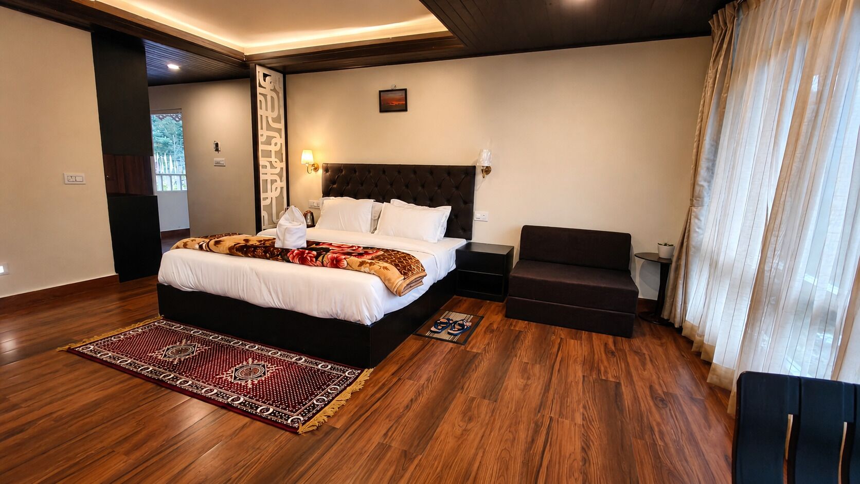 Una habitación de hotel moderna con una cama grande, un sofá, una mesita y vistas al exterior.