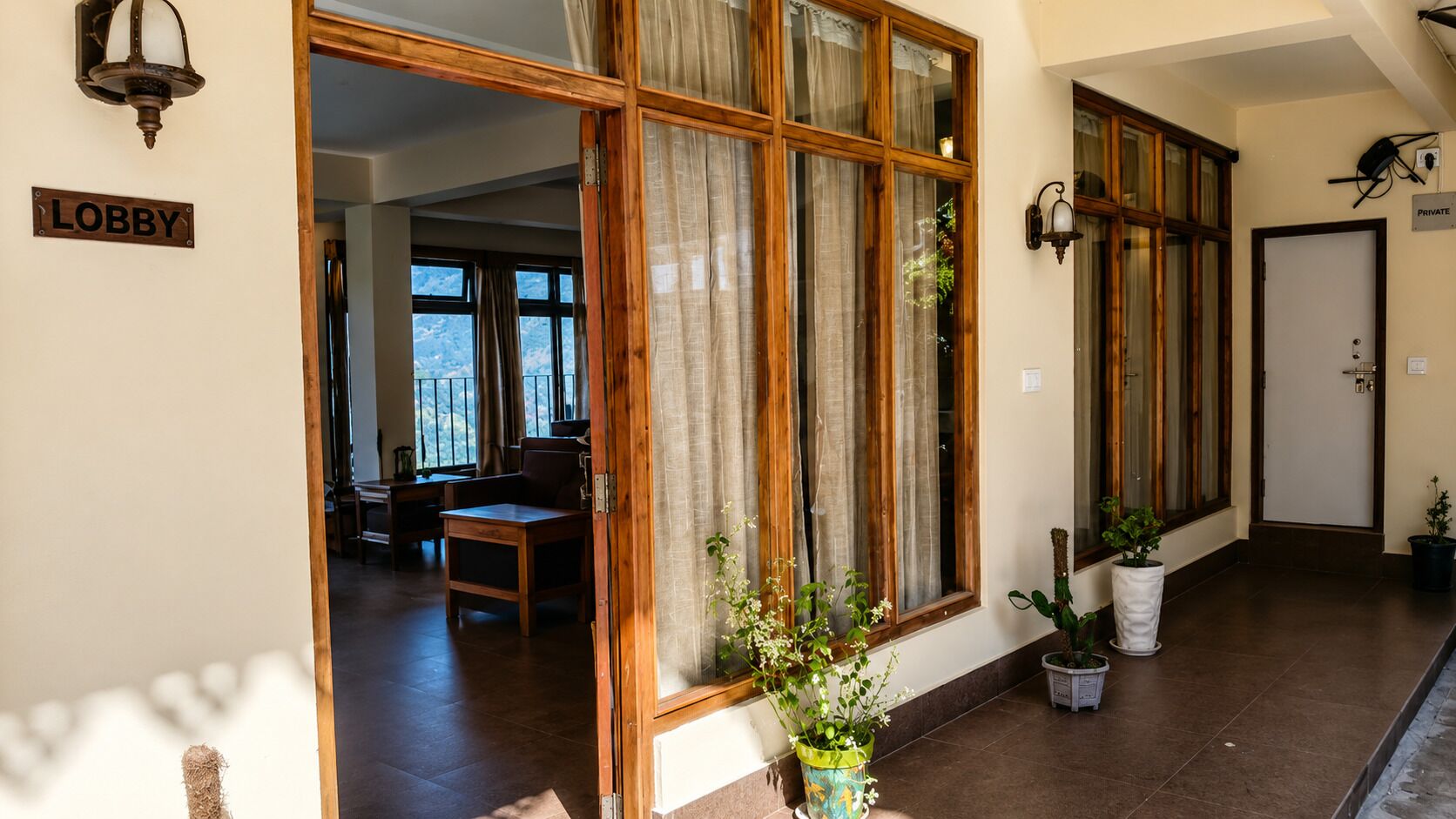 Un vestíbulo con una ventana de madera, un letrero que dice 'LOBBY' y plantas en macetas.