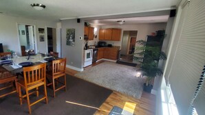 A spacious living area with a dining table, chairs, a TV, and a kitchen in the background. - Comfortable 2-bedroom house in Boise. Hot Tub. Fenced yard. Pet friendly. (Boise)