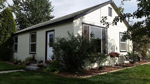 A single-story house with a gabled roof, white siding, and a front porch with steps. - Comfortable 2-bedroom house in Boise. Hot Tub. Fenced yard. Pet friendly. (Boise)