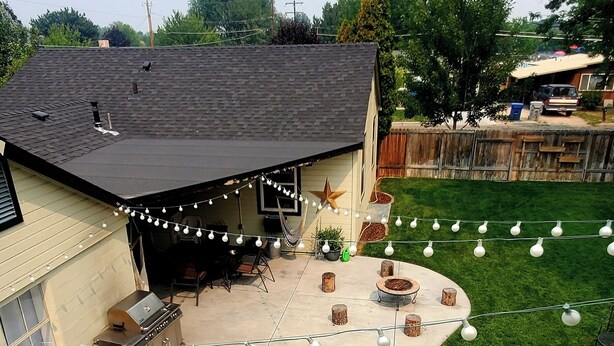 A backyard with a hot tub, outdoor seating, string lights, and a lawn. - Comfortable 2-bedroom house in Boise. Hot Tub. Fenced yard. Pet friendly. (Boise)
