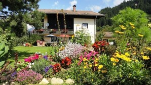 Ein Haus mit einem Garten voller bunter Blumen und einem Berg im Hintergrund.