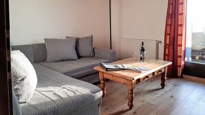 Een woonkamer met een bank, een houten salontafel en een raam met gordijnen.