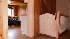 Un interior de madera con un comedor, una puerta blanca y una barandilla de madera.