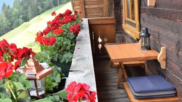 Una cabaña de madera con un porche de madera, una mesa y sillas.