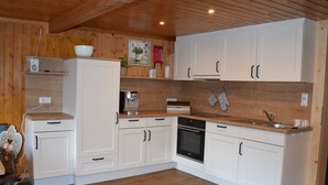 Una cocina moderna con armarios blancos, encimeras de madera, horno integrado y cafetera.