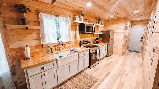 Interior de madera con cocina que incluye un lavabo, estufa, microondas y refrigerador.