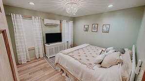 Un dormitorio con cama, televisión, aire acondicionado y candelabro.