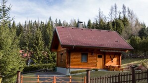 A wooden cabin with a red-tiled roof, surrounded by a wooden fence and a gravel driveway. - Holzhaus Klippitzblickhütte by Interhome (Bad St. Leonhard im Lavanttal)