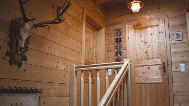 A wooden interior with a staircase, a mounted deer skull, and a patterned rug. - Holzhaus Klippitzblickhütte by Interhome (Bad St. Leonhard im Lavanttal)