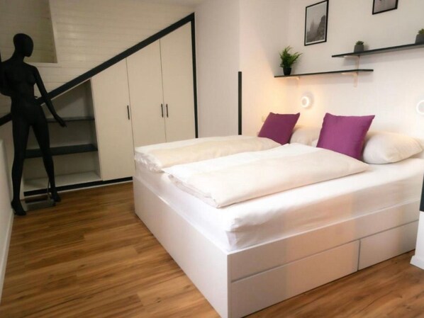 Ein modernes Schlafzimmer mit Bett, Einbauschrank und einer Treppe.