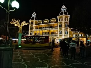 Ein großes, beleuchtetes Gebäude mit mehreren Balkonen und einem markanten Turm.