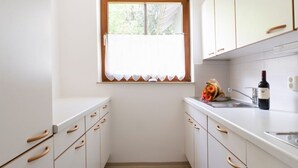 A narrow kitchen with white cabinets and wooden flooring. - Apartment Ahorn by Interhome (Feistritz im Rosental)