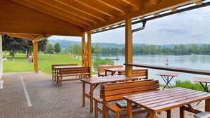 An outdoor wooden deck with picnic tables and benches overlooking a lake.