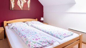 A single bed with floral bedding, a wooden headboard, a nightstand, a lamp, and a painting on the wall. - Apartment Esche by Interhome (Feistritz im Rosental)