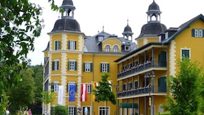 A yellow building with multiple balconies and a central tower. Flags are displayed outside. - Erle in Feistritz im Rosental by Interhome (Feistritz im Rosental)