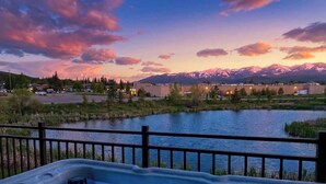 A hot tub with a view of mountains and a lake at dusk. - 4 Bd / 4 Bth | Luxury Condo | Hot Tub | Sleeps 10 (Whitefish)