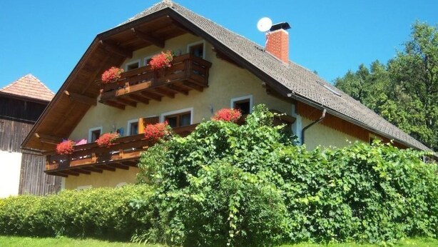 A traditional chalet with a sloped roof, wooden balconies with flower boxes, and a chimney. - Typ 1 im Haus Huber in Bleiburg by Interhome (Bleiburg)