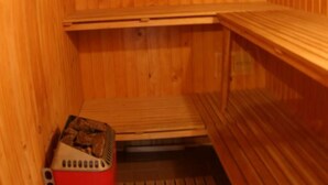 A sauna with wooden walls and benches, a red heater, and a small window. - Typ 1 im Haus Huber in Bleiburg by Interhome (Bleiburg)