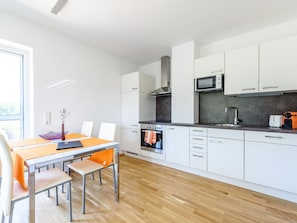 Eine moderne Küche mit weißen Schränken, einem Einbauofen, einer Mikrowelle und einem Toaster.